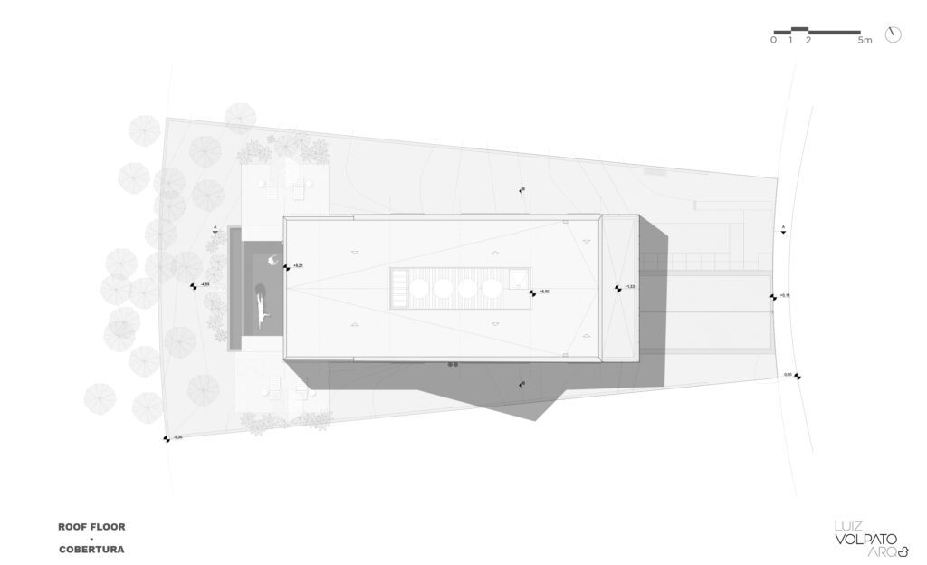 A planta baixa de um nível de telhado mostra um edifício retangular com uma área central aberta com estruturas circulares. Dois pontos de entrada estão nos lados superior e inferior. Árvores e caminhos pavimentados cercam o edifício. O norte é indicado no canto superior direito. Créditos do design no canto inferior direito. - Luiz Volpato Arquitetura