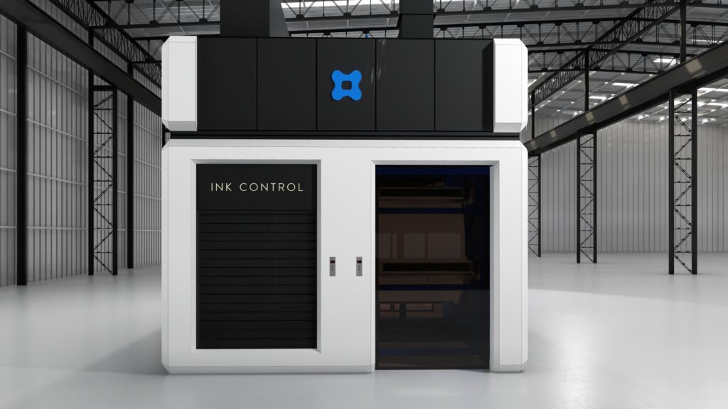 Uma grande máquina industrial está posicionada em um amplo armazém com tetos altos. A máquina tem um exterior branco com painéis pretos rotulados como "INK CONTROL" à esquerda e uma seção aberta à direita. Acima, há um logotipo azul. O espaço é claro com vigas de metal visíveis ao fundo. - Luiz Volpato Arquitetura