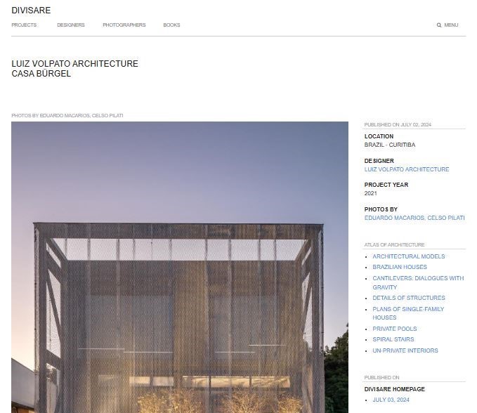 Captura de tela de uma página da web da Divisare com uma foto da Casa Burgel por Luiz Volpato Architecture. A imagem mostra um edifício moderno com uma fachada de malha. O menu inclui seções como "Projetos" e "Fotógrafos". A localização é listada como Curitiba, Brasil. - Luiz Volpato Arquitetura