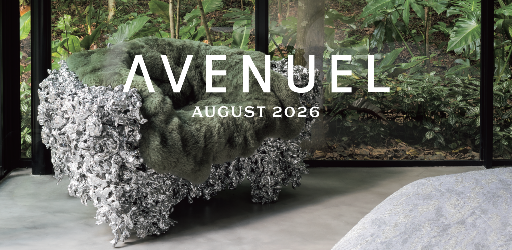 Uma poltrona verde estofada com uma base metálica texturizada está posicionada junto a paredes de vidro com vista para uma vegetação exuberante. As inscrições “AVENUEL” e “AGOSTO DE 2026” aparecem em letras brancas em negrito sobrepostas na imagem. O piso de concreto e parte de um tapete são visíveis na sala moderna. - Luiz Volpato Arquitetura