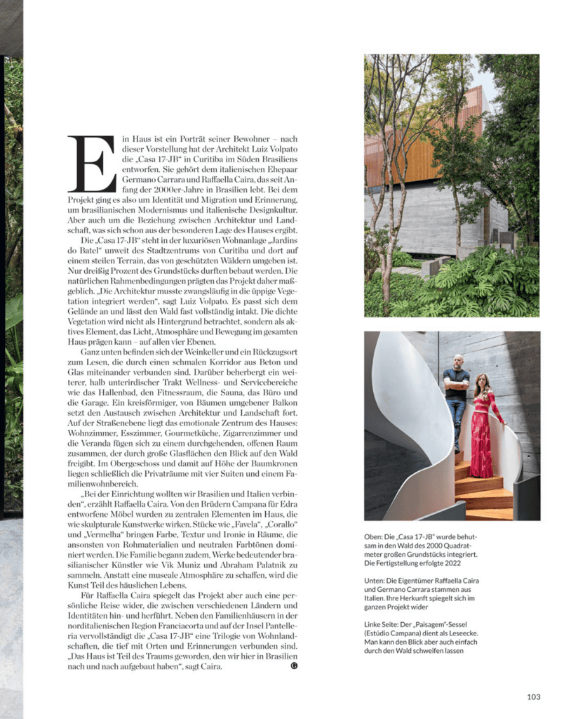 Uma página de revista exibe um texto em alemão à esquerda e, à direita, uma foto de uma casa moderna com paredes brancas curvas, um portão de madeira, árvores e degraus, com duas pessoas em pé na frente, parcialmente ocultas pela arquitetura. O número da página, 103, está na parte inferior. - Luiz Volpato Arquitetura